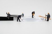Miniature construction worker is working on a magnifying glass on a white background.
