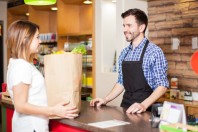 Une cliente à l'épicerie, au magasin, avec un caissier, emballe ses courses