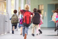 Group of elementary school kids running at school, back view