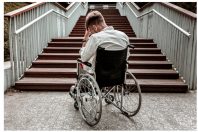 Laconic image of disabled man sitting in front of the stairs