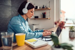 Woman using laptop and listening music on a headphones