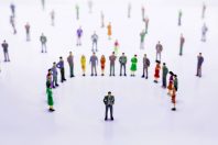 Group of miniature people over white background standing in line
