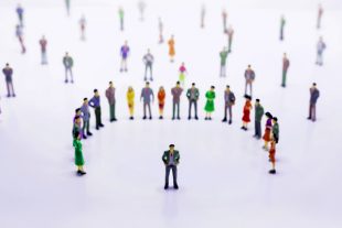 Group of miniature people over white background standing in line
