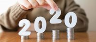 2020 New year saving money and financial planning concept. Female hands putting white number 2020 on stack of coins. Creative idea for business growth, tax payment, investment and banking.