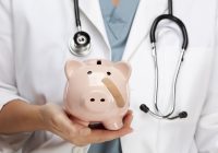 Female Doctor with Stethoscope Holding Piggy Bank with Bandage on Face.