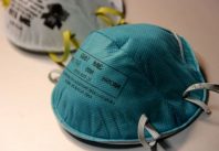 n95-type-masks-lying-atop-of-a-silver-table-top-one-turquoise-in-color-in-the-foreground-725x483