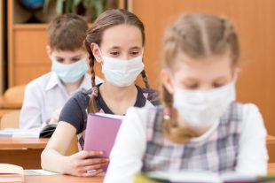 Schoolkids with medicine mask on faces against virus in classroo