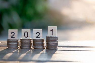 Coins stacks and Text of 2021 number written on wooden blocks on top of coin with sunset nature background, Business and Saving money for new life new year concept, Selective focus.