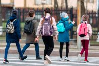 School children cross the road in medical masks. Children go to