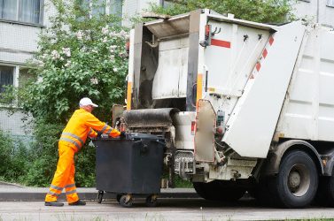 Worker of urban municipal recycling garbage collector truck loading waste and trash bin