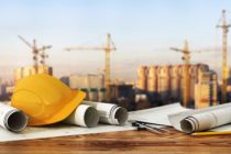 Concept of construction and design. 3d render of blueprints and designer tools on the panorama of construction site.