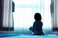 Little baby child sitting on bed playing with the doll in the da