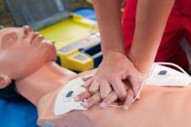 Practicing defibrillator CPR procedure on a dummy
