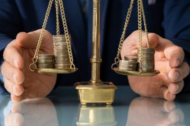 Lawyer's Hand Protecting Justice Scale With Coins