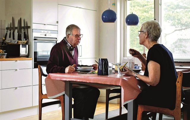 Full length of senior couple eating food at dining table