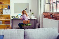 studentin sitzt zuhause am schreibtisch und arbeitet am laptop