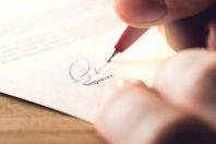 Man writing signature with pen on paper. Settlement for acquisit