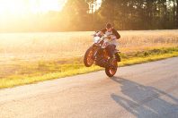 Teenage boy on a dirtbike motorcycle doing a wheelie at sunset