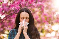 Woman blowing nose because of spring pollen allergy