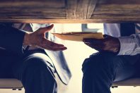 Business people sending documents under the table
