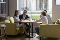 Four millennial businesspeople negotiating in modern office