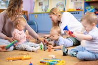 Friends with toddlers playing on the floor in montessori centre