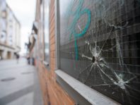 Bullet hole in a window with graffiti in an alleyway