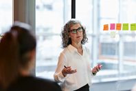 Senior confident businesswoman giving presentation in board room at office