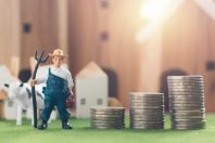 Miniature Farmer and cow figure model with money coin stack on S