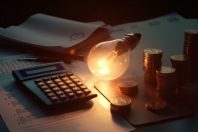 Electricity bill with light bulb, several coins, calculator and