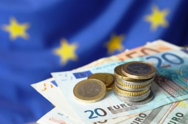 Coins and banknotes against European Union flag, closeup. Space