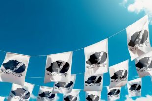 Flag of Corsica - France against the sky, flags hanging vertically