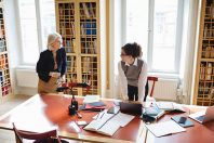 Senior lawyer discussing with female coworker at table in library