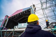 team building up the music stage for a festival, with personal protective equipment