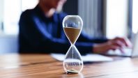 Close up view of hourglass measuring time on wooden table