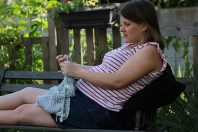 Une femme enceinte tricote sur un banc