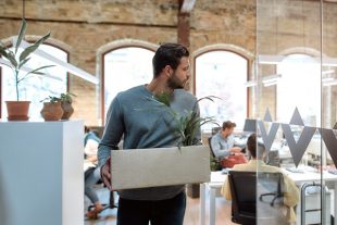 Saying good bye. Handsome man in casual wear holding box with personal things and leaving modern office. Quit concept. Office life