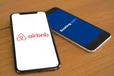 Logos der Buchungsportale Airbnb und Booking.com werden auf nebeneinanderliegenden Smartphones angezeigt, Urlaub, Ferienwohnung, Hotel, Unterkunft, Reisen, Buchen, 2023