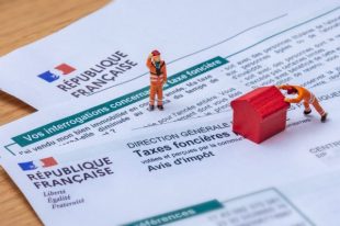 Clamart, France - 6 septembre 2022 : Détail d'un avis d'impôt français sur les taxes foncières avec de petits personnages déplaçant une maison jouet rouge en bois