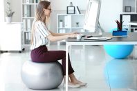 Young businesswoman sitting on fitball while working in office