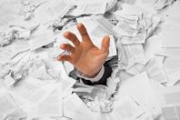 Hand reaches out from crumpled papers