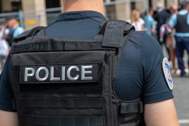 Paris, France - 25 juillet 2024: Marquage "POLICE" en gros plan écrit à l'arrière d'un gilet pare-balles porté par un officier de police. Concepts de sécurité, de criminalité et d'affaires policières