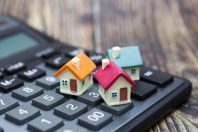 Buy home. House is placed on the calculator. Planning savings money of coins to buy a home concept for property, mortgage and real estate investment.