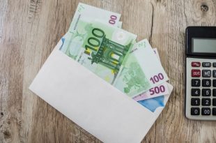 100 euros in a white envelope and part of the calculator on the table