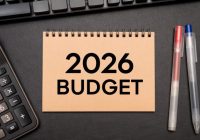 2026 BUDGET text on Notebook with calculator and office supplies. Budget planning concept.