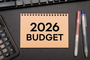 2026 BUDGET text on Notebook with calculator and office supplies. Budget planning concept.