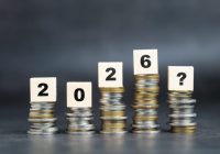 Stack of coins with wooden blocks, symbolizing future financial growth, economic uncertainty, and investment planning for the year 2026