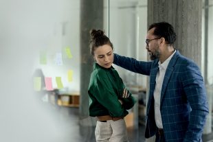 Mature man abusing his younger colleague, concept of harassment at workplace.