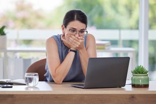 Surprise, mistake or error with a business woman looking shocked while working on a laptop in her office. Computer, glitch and problem with a scared female employee worried about a system failure