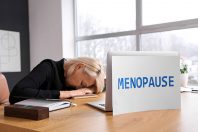 Mature businesswoman and laptop with word MENOPAUSE on table in